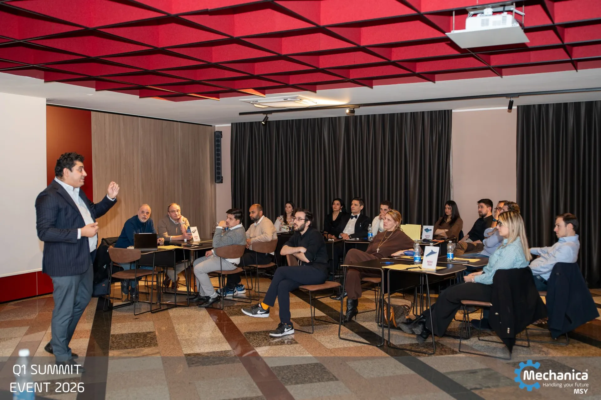 Wide view of the summit room with the whole company seated